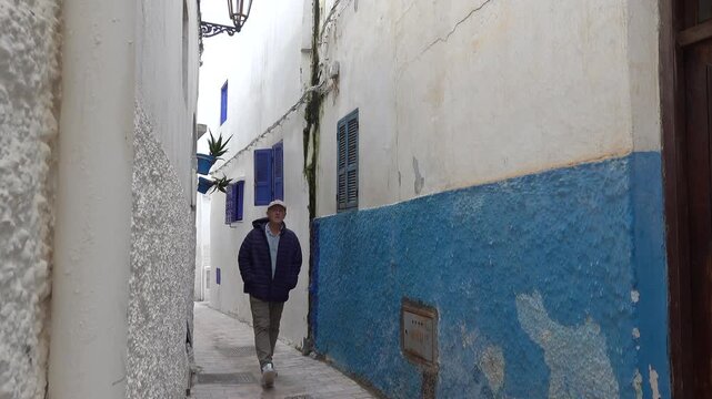 Rabat, Morocco A tourist man walks in the picturesque back alleys of the Kasbah Oudaya, The Kasbah of the Udayas, also spelled Kasbah of the Oudaias or of the Oudayas.
