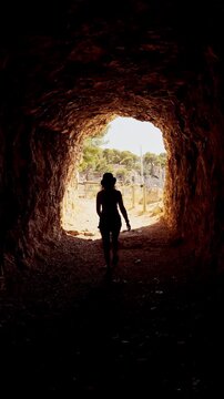 Young woman emerging from a rocky tunnel with a panoramic view of Port Miou bay in Calanques National Park, France.