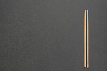 Horizontal textured black background with bamboo chopsticks