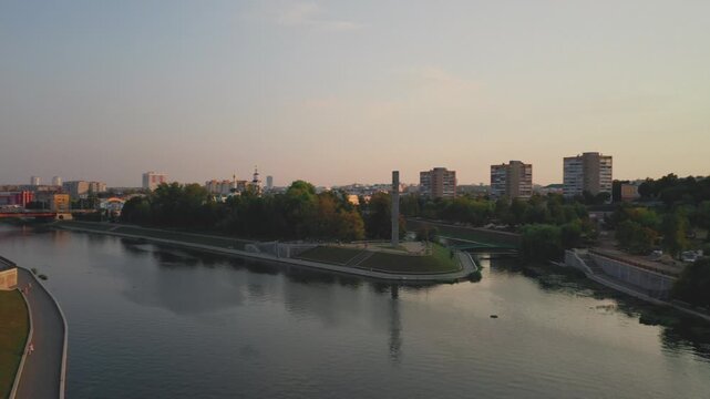 Aerial evening view of Orel city in Russia with river, Strelka, main buildings, churches and roads. Beautiful cityscape with lights reflecting on water at sunset, showing urban architecture, skyline.
