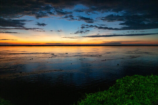 Paisagem tropical de rio com pequena canoa ao centro e c&eacute;u de fim de tarde - Urucurituba, munic&iacute;pio do estado do Amazonas - Brasil 1