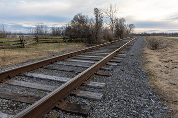 Obraz premium Railway tracks running into the distance in early spring. Rural railroad line.