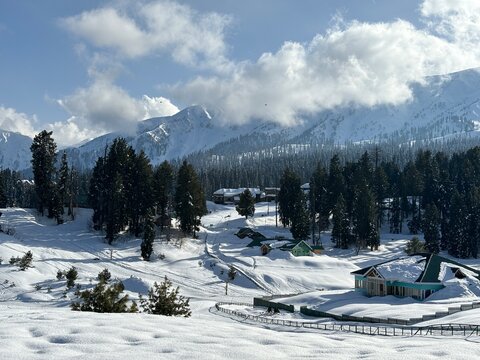 Beautiful natural landscape of Gulmarg featuring rolling green meadows, pine forests, snow-capped Himalayan peaks, and fresh mountain air in Kashmir.