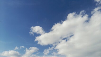 Fototapeta premium Fluffy White Cumulus Clouds in a Vibrant Deep Blue Sky on a Bright Sunny Day