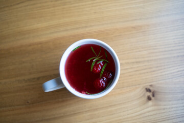 overhead mug red tea wooden surface cozy minimalist scene, warm beverage topped cranberry and rosemary sprig, faint steam rising, soft