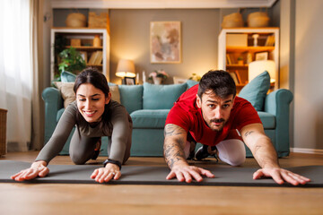 Fototapeta premium Couple doing back stretching out while working out at home