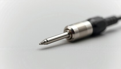 Fototapeta premium A detailed close-up shot of a gleaming silver audio jack plug on a simple, light grey background, highlighting connectivity.