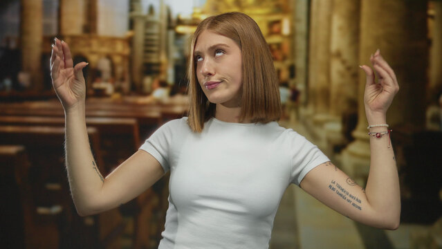 Young blonde woman arms raised in mocking gesture inside church interior; mockery gossip disbelief.