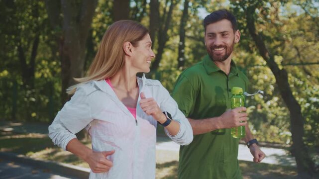 Group of fitness enthusiasts Jogging on woodland path displaying hydration gear and tracking technology