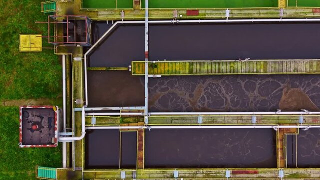 View of a water treatment facility showing various sections, pipes, and water flow. The scene captures the ongoing process of water treatment in daylight.