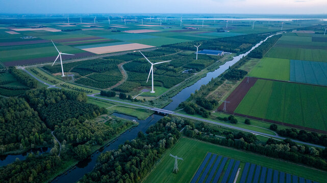 Aerial View of Wind Farm with Turbines Over Agricultural Fields and Canal Demonstrating Renewable Energy Infrastructure in Rural Landscape