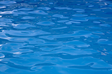 Obraz premium Abstract background of deep blue swimming pool water texture with ripples and selective focus. Concept of freshness, summer