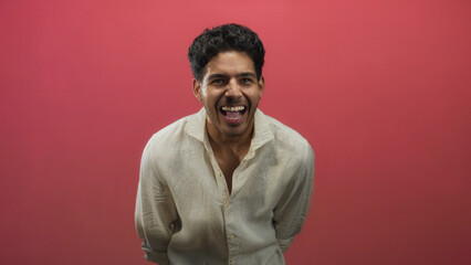 Obraz premium Man smiling showing teeth and laughing with clenched hands wearing linen shirt in studio; joy confidence.