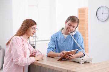 Obraz premium Medical assistant answering phone and helping patient at reception in clinic