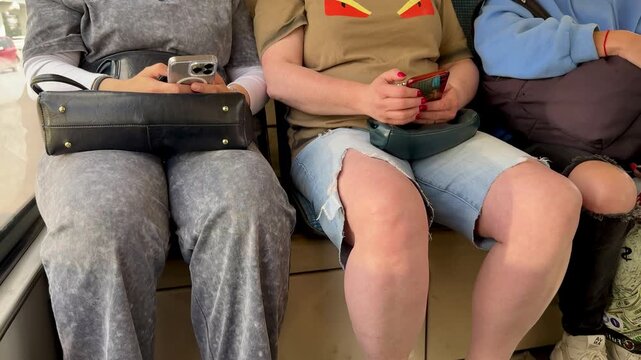 Three Seated Legs In Different Footwear On Subway Floor, Yellow Flipflops And Sneakers, Ripped Denim Hem And Gray Sweatpants, Casual Travel Vibe, Contrast Of Textures And Colors, Everyday.