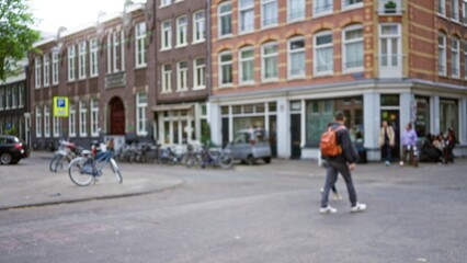 Blurred man with backpack walking in european city square surrounded by historic buildings with bokeh bicycles, creating an outdoor urban ambiance.