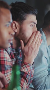 Intense sports viewing, Friends and colleagues share tense moments as they watch live sports game in low lighting