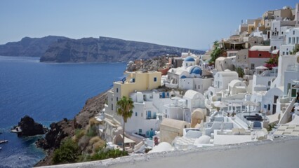 Naklejka premium Mediterranean cliffside village defocused with white domes and blue sea in soft blur outdoor; background backdrop copyspace calm.