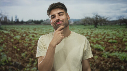Man with hand on chin and thoughtful gaze in forest clearing bathed in soft natural light under...