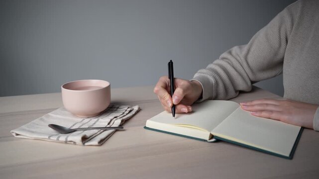 Hand picking up pen to continue writing at minimal workspace