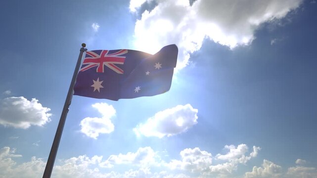 Australia Flag waving on a Flagpole from a Moving Angle in front of a blue sky with clouds	