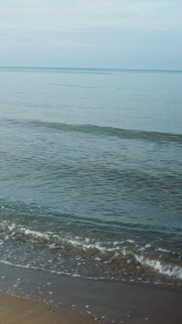 Peaceful seaside scene showing gentle waves rolling onto an empty beach with a lifeguard tower, evoking solitude and coastal calm, vertical video