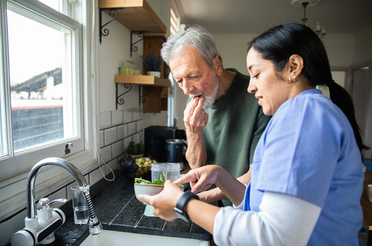 Caregiver helping senior man prepare a healthy meal at home
