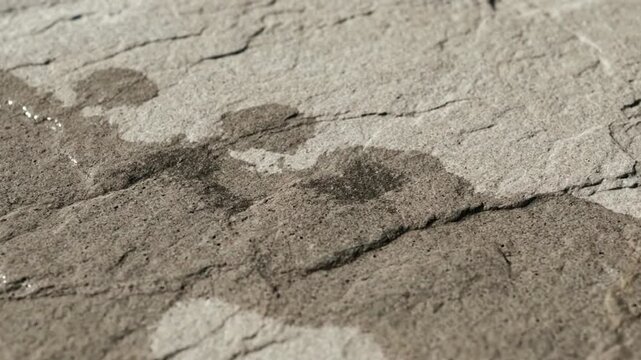 Water spreading and wetting a grey stone surface