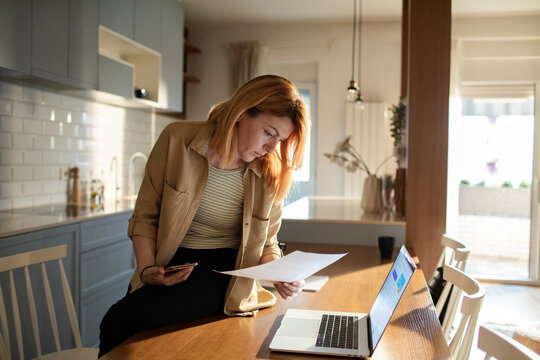 Young woman reviewing finances at home kitchen table