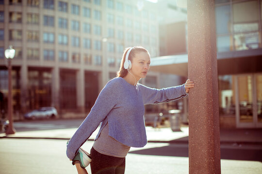 Young woman stretching before run in city street