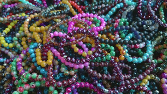 A vibrant pile of handmade beaded bracelets in many colors and patterns, capturing the lively spirit of artisan crafts and local street markets.