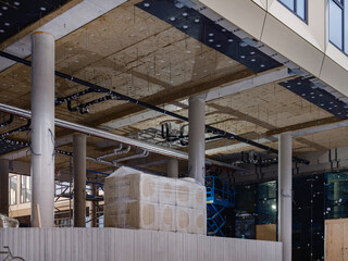 Interior of commercial building under construction showing exposed ceiling, piping and insulation work in progress