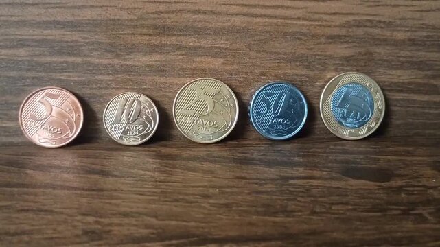 Current Brazilian coins, real coins, all denominations in circulation on a wooden background.