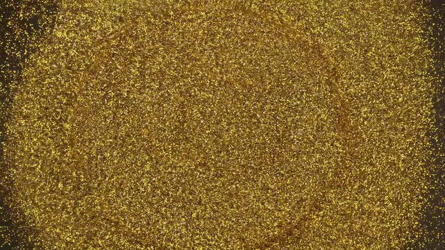 Exploring the patterns of golden particles in motion across a black background during an art project in a local studio