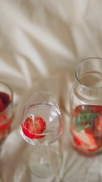 Fresh Organic Strawberries in Glass and Infused Water Pitcher on Beige Fabric Background
