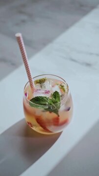 Person Putting a Straw into Refreshing Fruit Infused Water with Mint