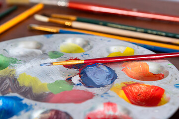 Fototapeta premium A paint brush sitting on top of a paint pallette filled with colorful paint