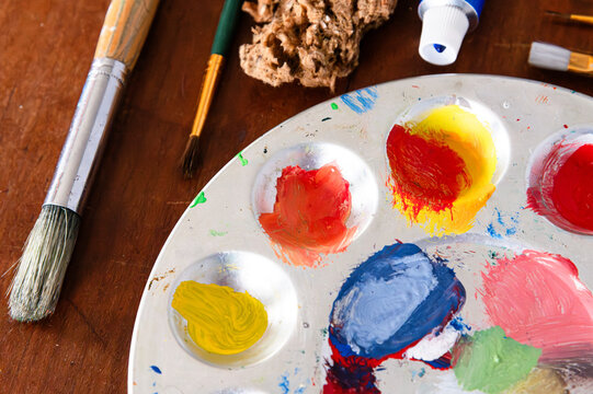 Top view of a paint pallette and paint supplies, including brushes