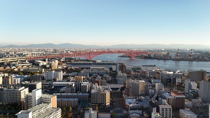 Naklejka premium Osaka, Japan at sunset: Aerial Drone View of Tempozan Bridge, Tempozan Wharf, Harbour, Port of Osaka, Harbour, Osaka Bay, Ferris Wheel, City Skyline, Evening Colours in Konohana and Minato Ward