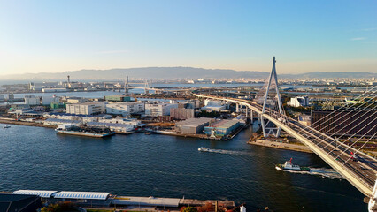 Obraz premium Osaka, Japan at sunset: Aerial Drone View of Tempozan Bridge, Tempozan Wharf, Harbour, Port of Osaka, Harbour, Osaka Bay, Ferris Wheel, City Skyline, Evening Colours in Konohana and Minato Ward