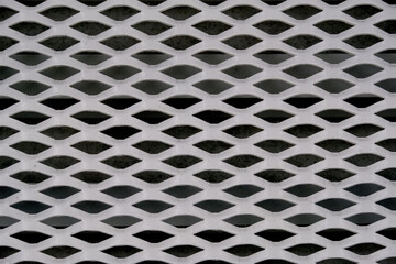 Abstract geometric pattern of a white expanded metal mesh with dark background © Thanakrit