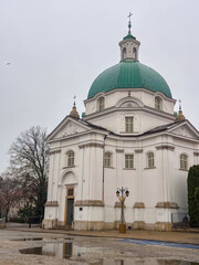 Fototapeta premium Historic church with green dome located in a town square during cloudy weather