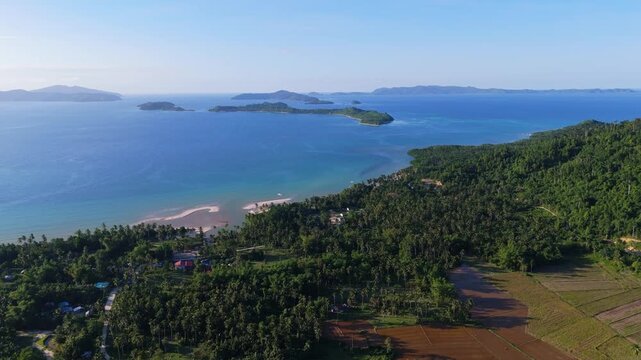 A cinematic aerial shot of Cagsalay Island in Port Barton, Palawan, capturing the lush greenery of the islands surrounded by the vast turquoise waters of the Philippines.