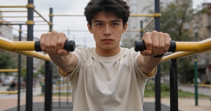 Young adult exercising outdoors on parallel bars workout fitness