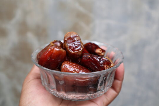 a hand holding dates fruit in a bowl
