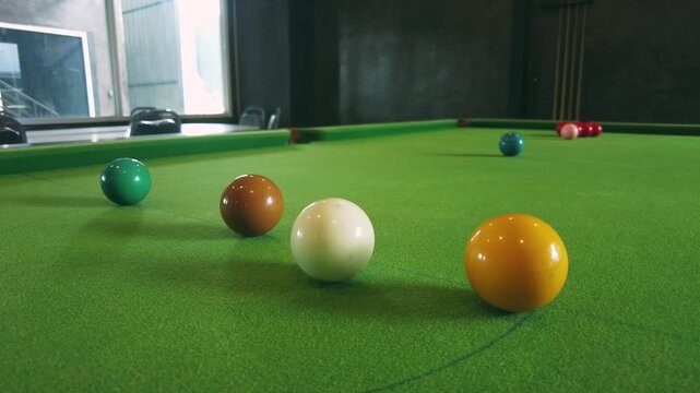 Colorful billiard balls arranged on a green felt table in a well-lit interior space showcasing the elements of cue sports for leisure and entertainment