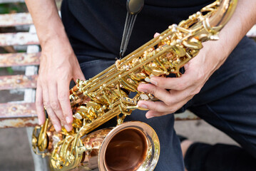 Obraz premium An elegant musician playing a golden saxophone outdoors. Close up.