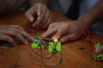 Curious hands working simple electrical circuit experiment diy science for kids project glowing light bulb shows success and excitement learning