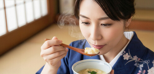 和室で湯気の立つ温かい茶碗蒸しを味わう着物姿の日本人女性
