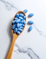 Blue pills spilling from a wooden spoon atop a marbled surface
